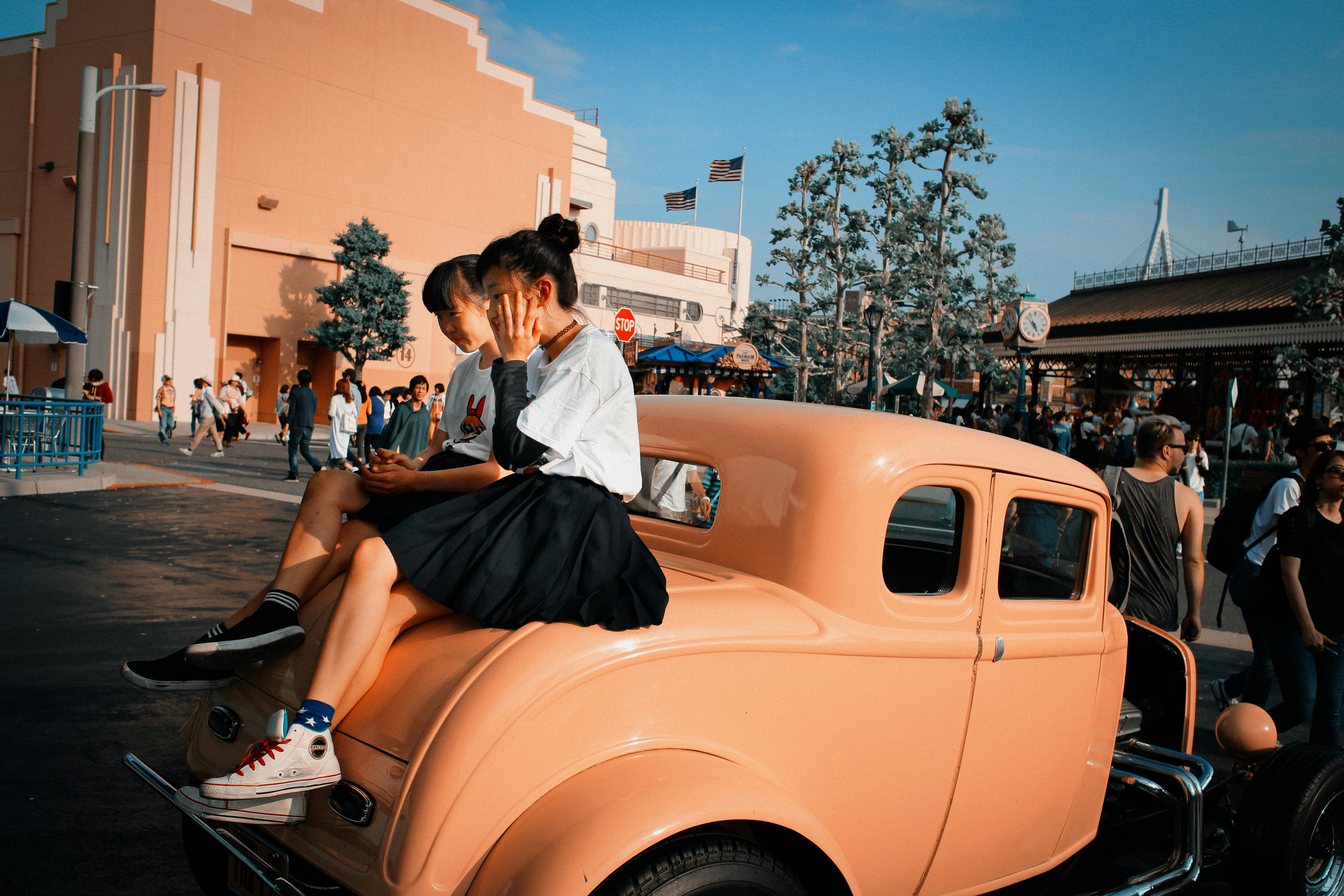 woman in white shirt and black skirt sitting on yellow car